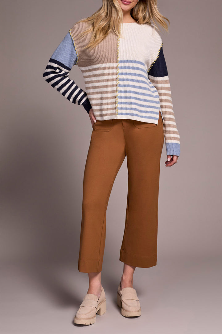 Person wearing a striped sweater and brown pants on a plain background