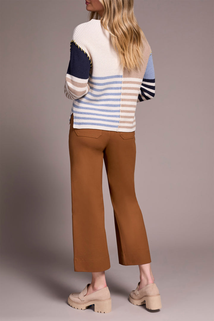 Person wearing a striped sweater and brown pants against a plain background