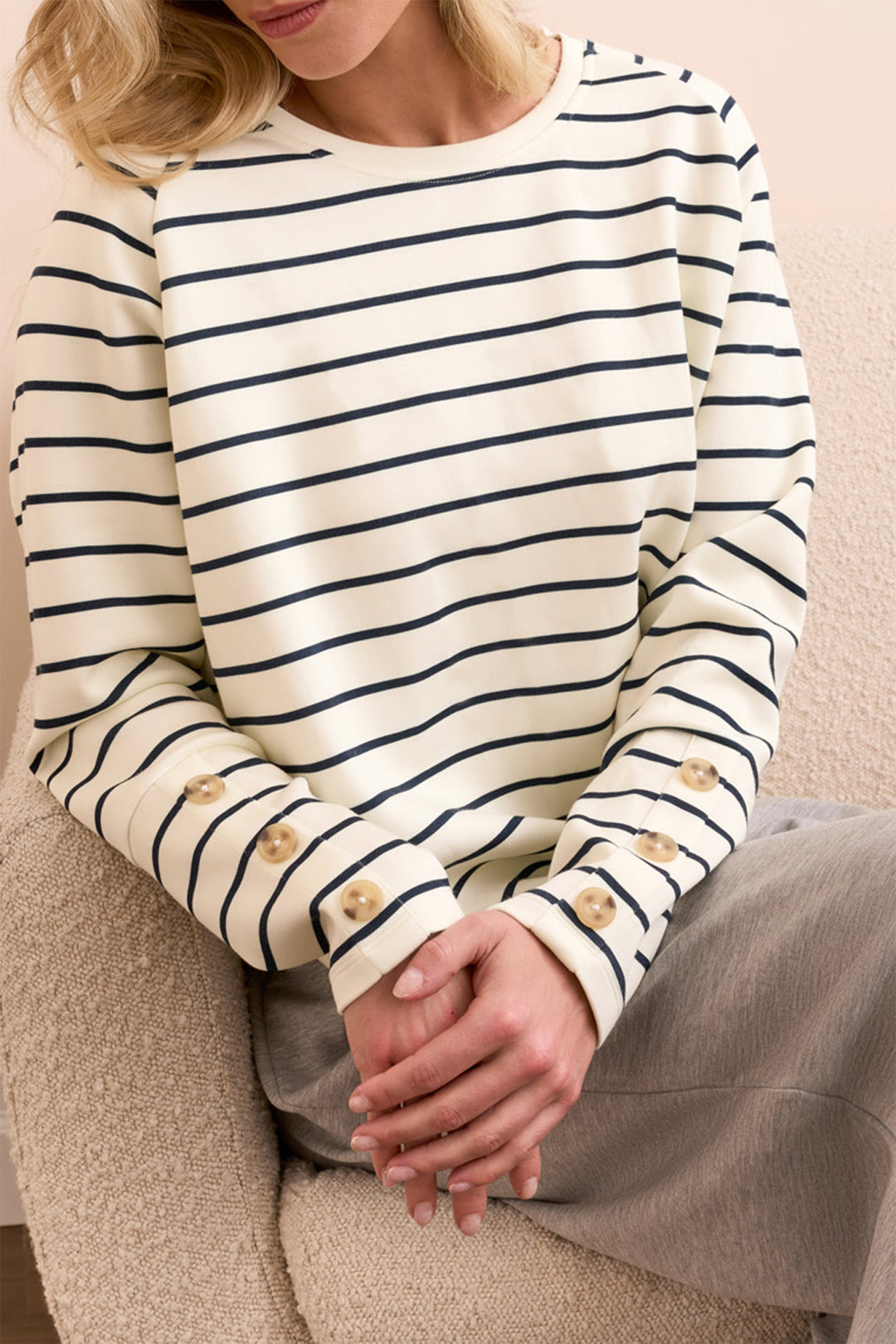 Person wearing a white and navy striped sweater with button cuffs.