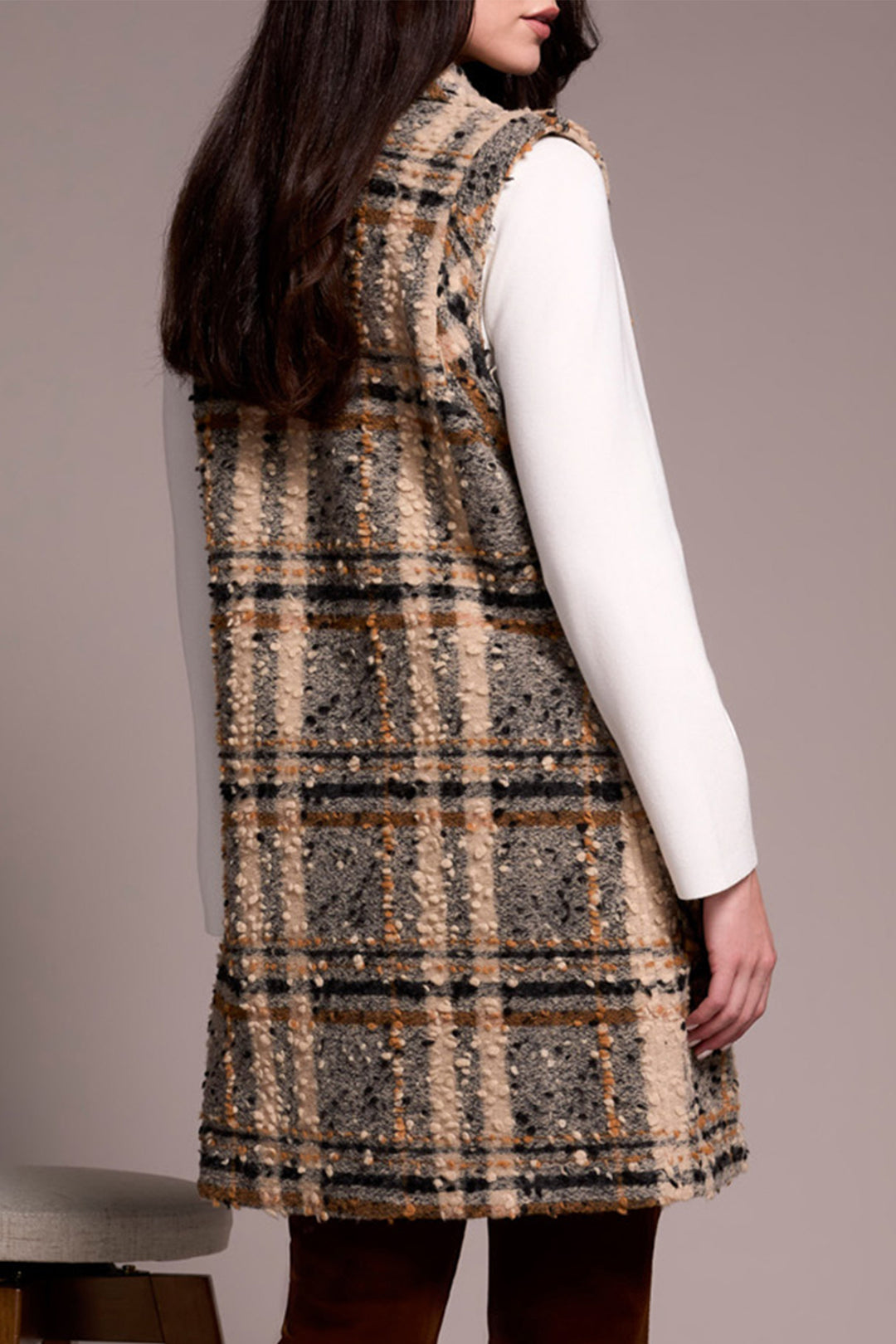 Person wearing a plaid dress over a white shirt against a plain background