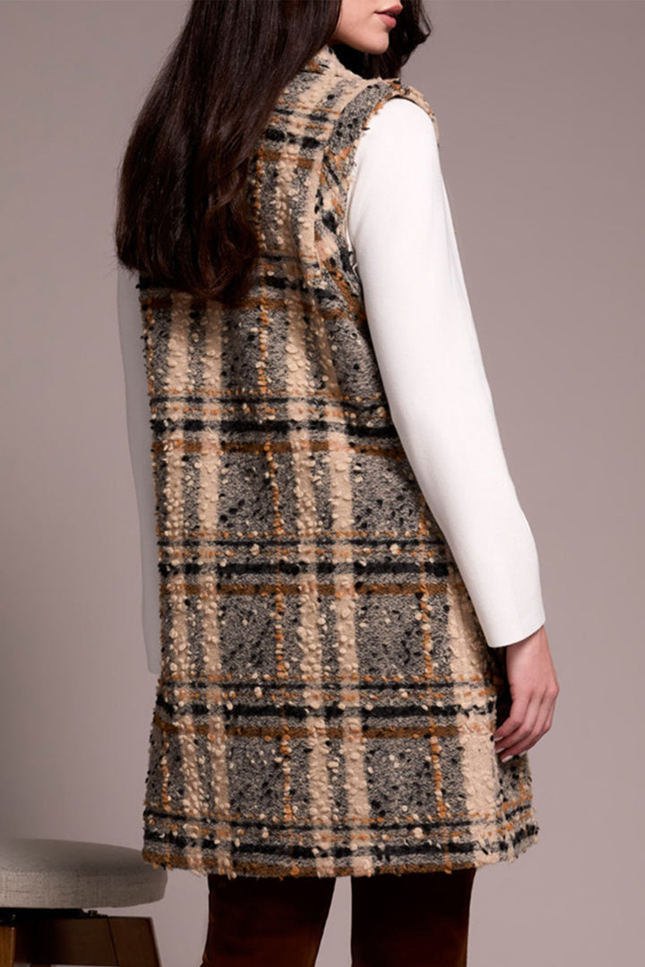 Person wearing a plaid dress over a white shirt against a plain background