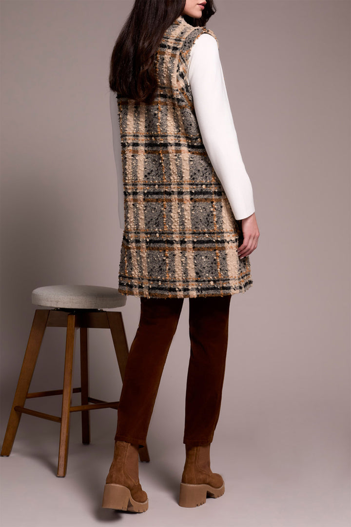 Person wearing a plaid vest over a white shirt with brown pants and shoes, standing against a plain background.