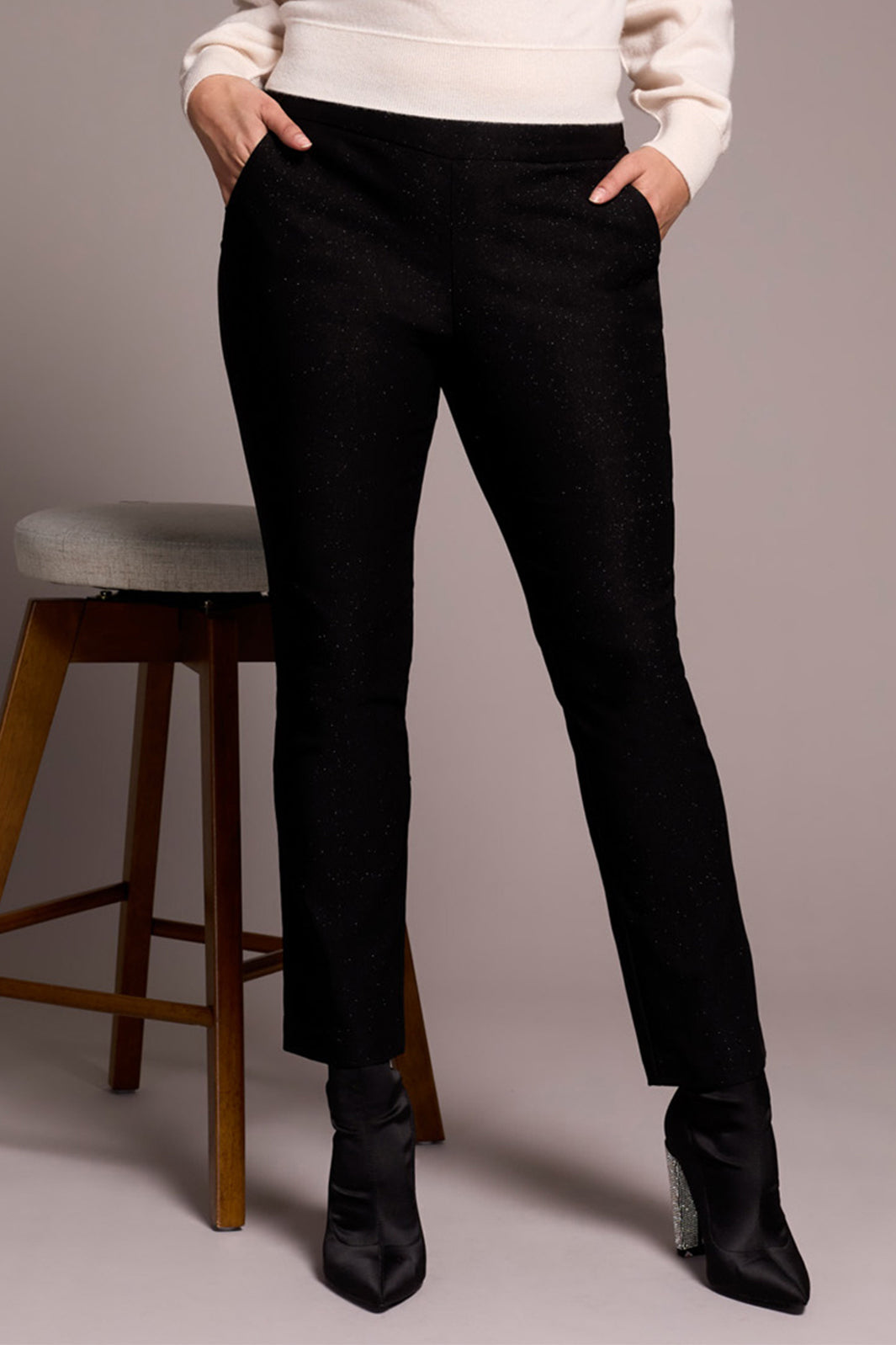 Person wearing black pants and black shoes on a neutral background