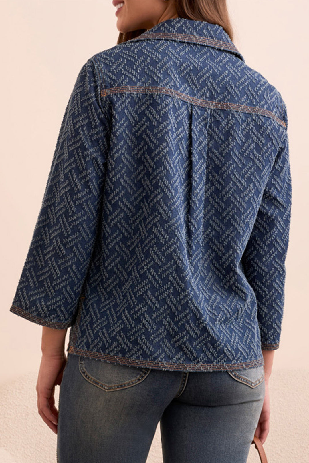 Person wearing a blue patterned jacket on a beige background