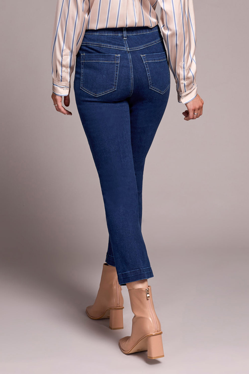 Person wearing blue jeans and a striped shirt on a plain background