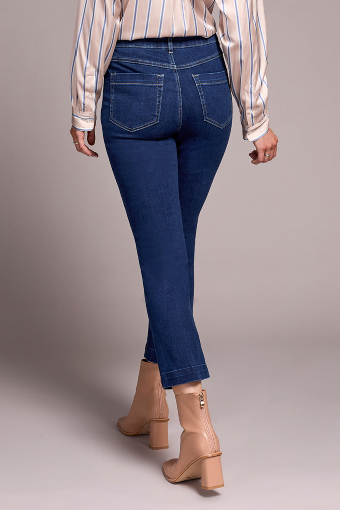Person wearing blue jeans and a striped shirt on a plain background