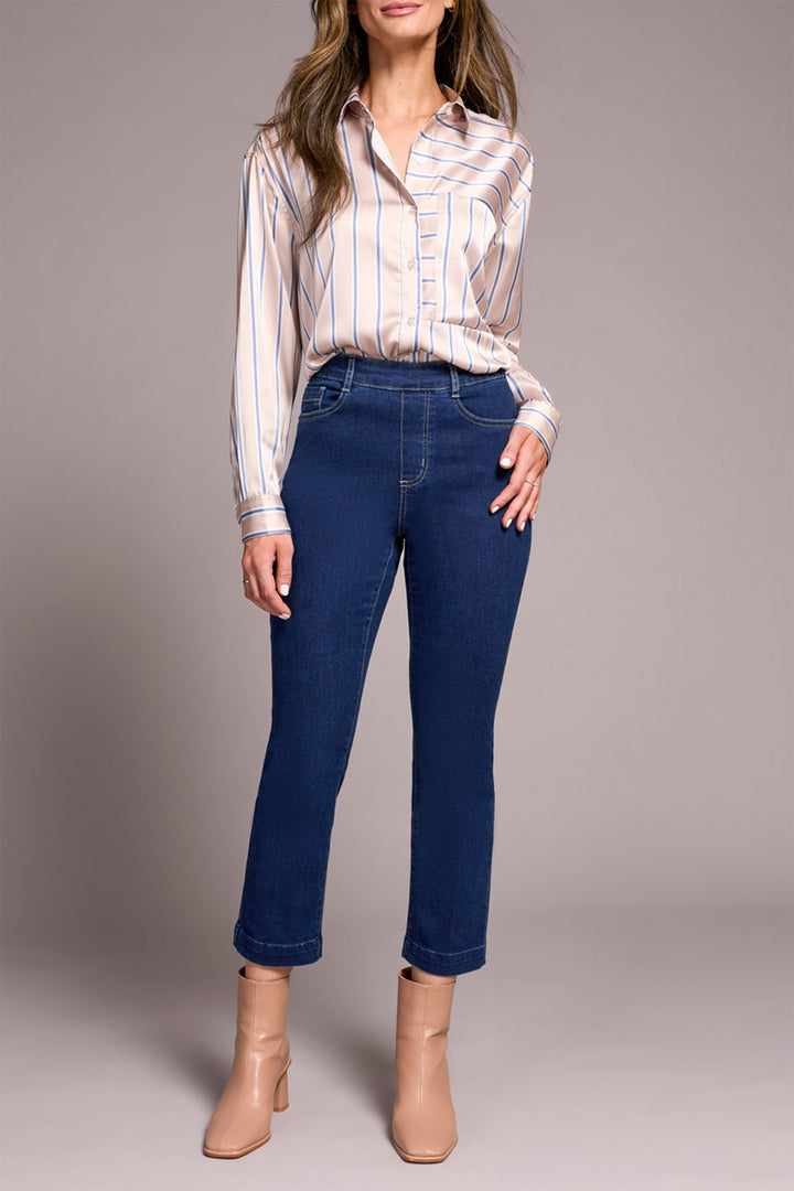 Woman wearing a striped shirt and blue jeans against a plain background