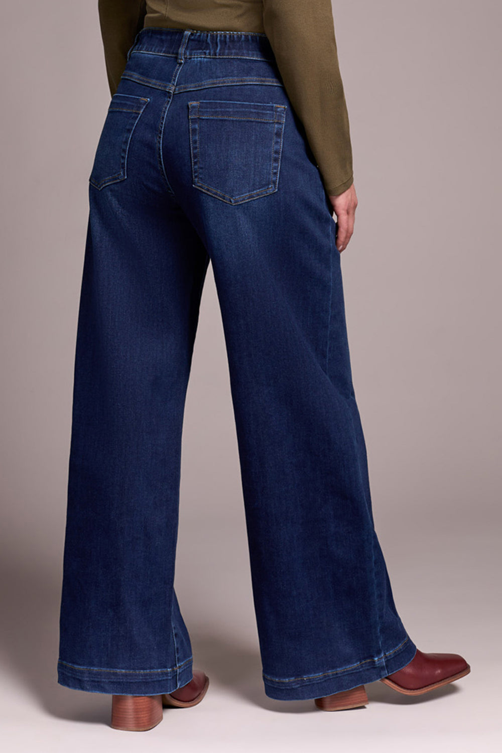Person wearing blue wide-leg jeans with a plain background