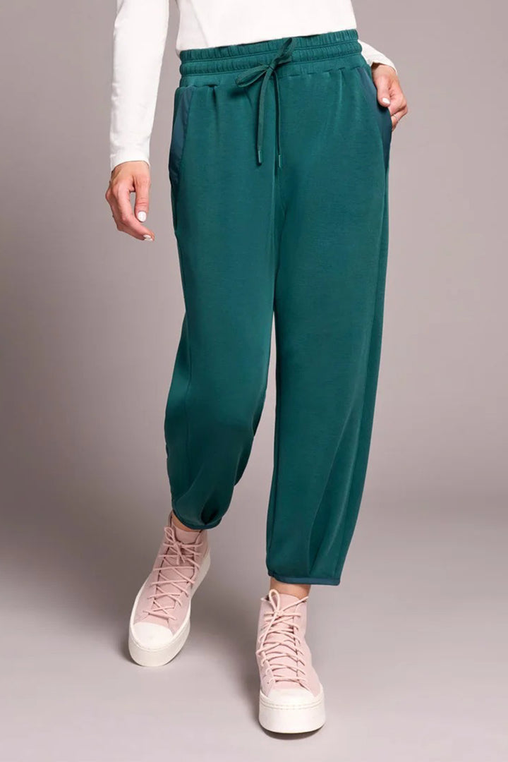 Teal jogger pants worn by a person on a plain background