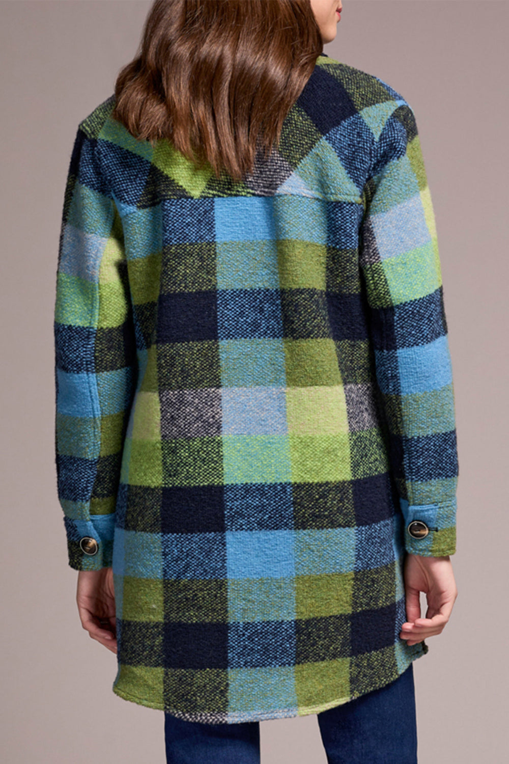 Person wearing a plaid coat with green, blue, and black pattern on a neutral background