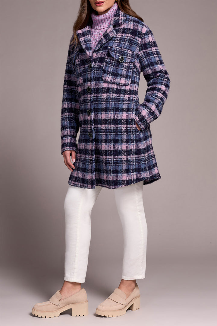 Person wearing a plaid coat over a turtleneck with white pants on a gray background