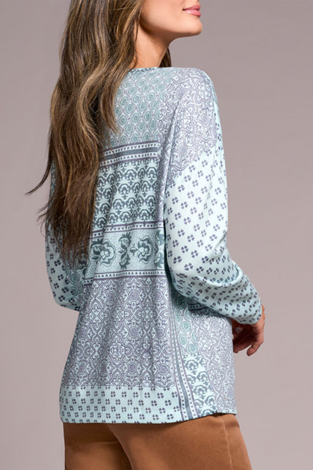Woman wearing a light blue patterned blouse against a beige background