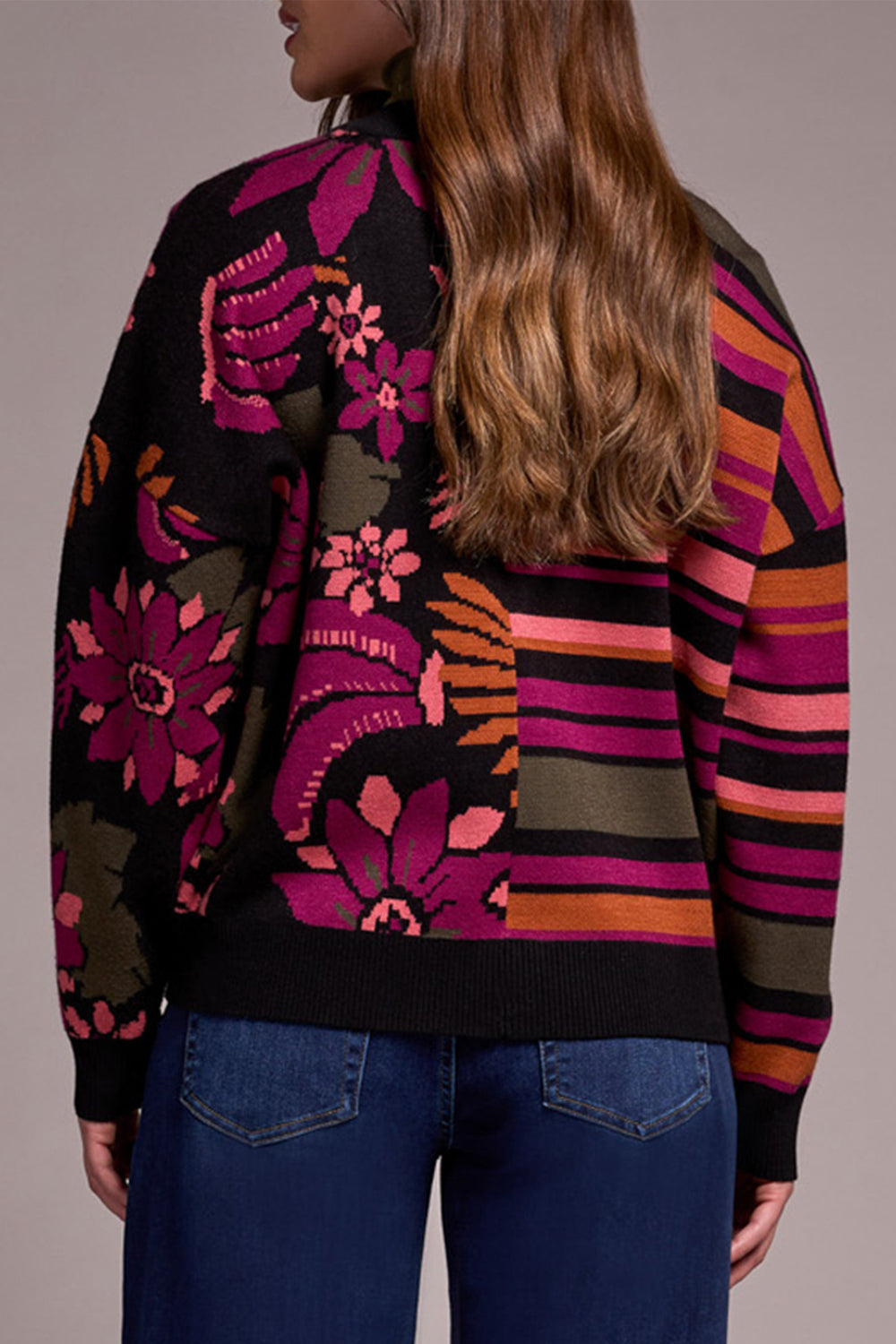 Person wearing a colorful patterned sweater with floral and abstract designs.