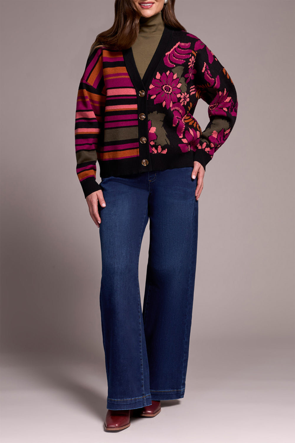 Person wearing a colorful cardigan with floral patterns and blue jeans on a neutral background