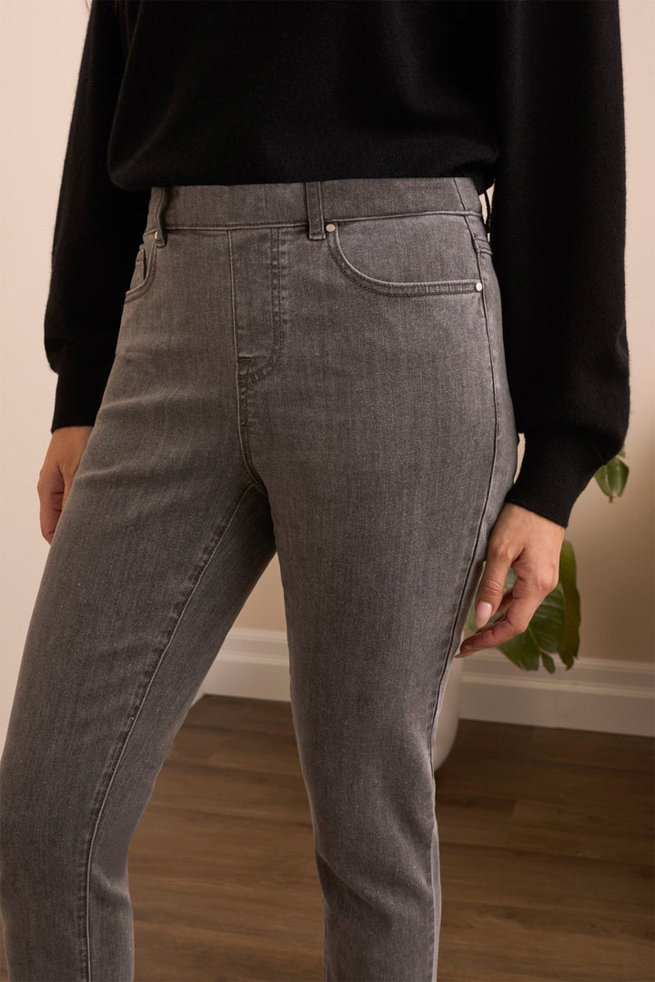 Person wearing gray jeans and a black sweater in a room with wooden flooring.