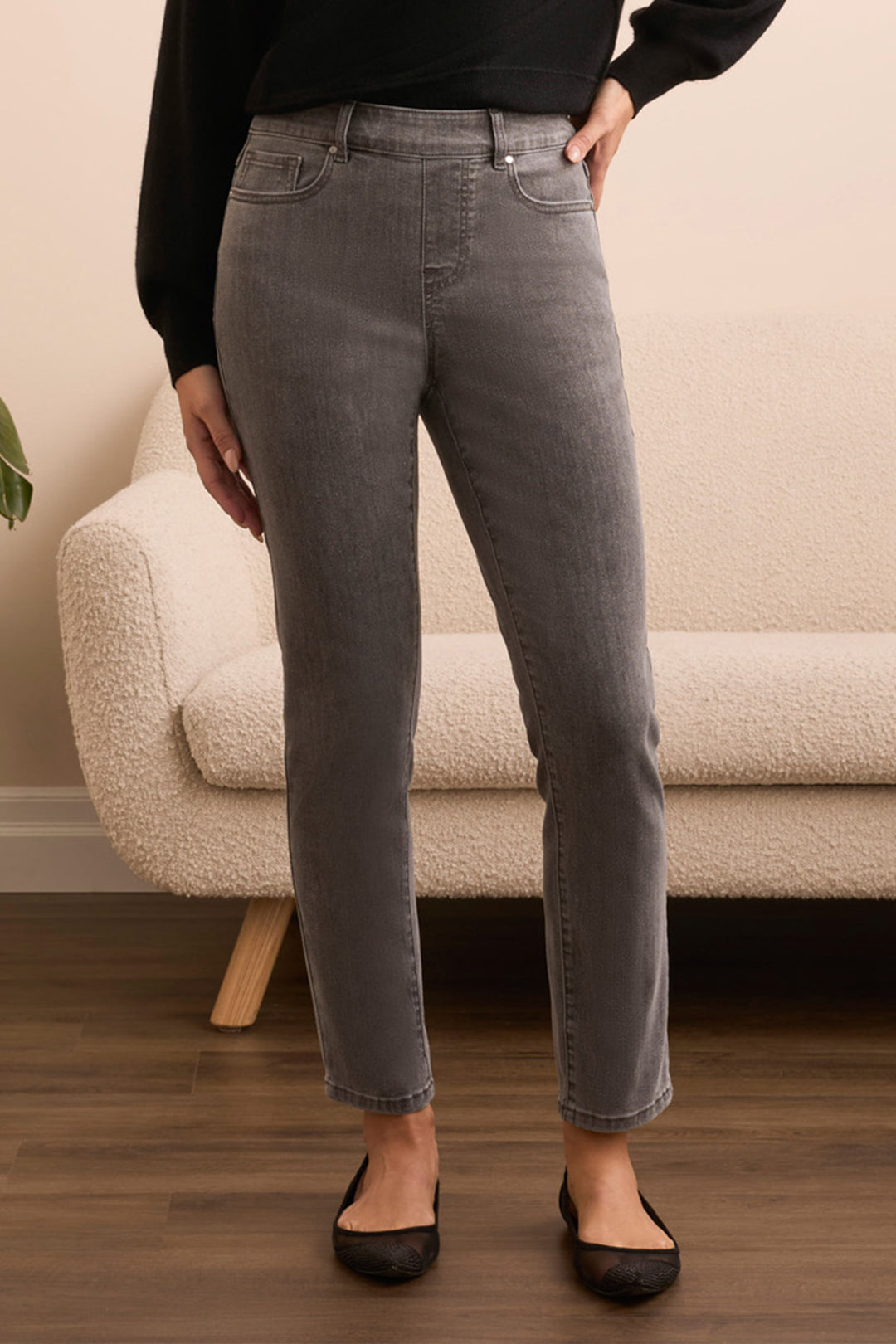 Person wearing gray jeans standing in a room with a beige sofa.