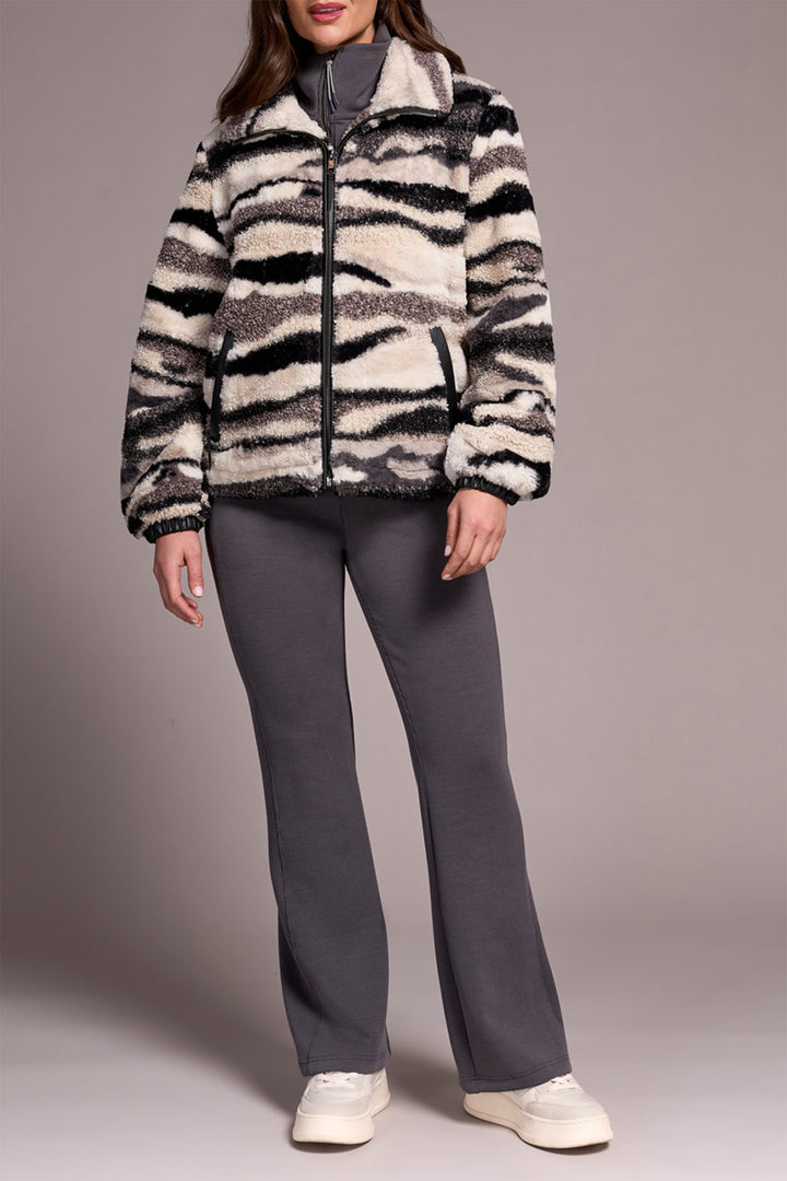 Person wearing a zebra-striped jacket and gray pants on a plain background