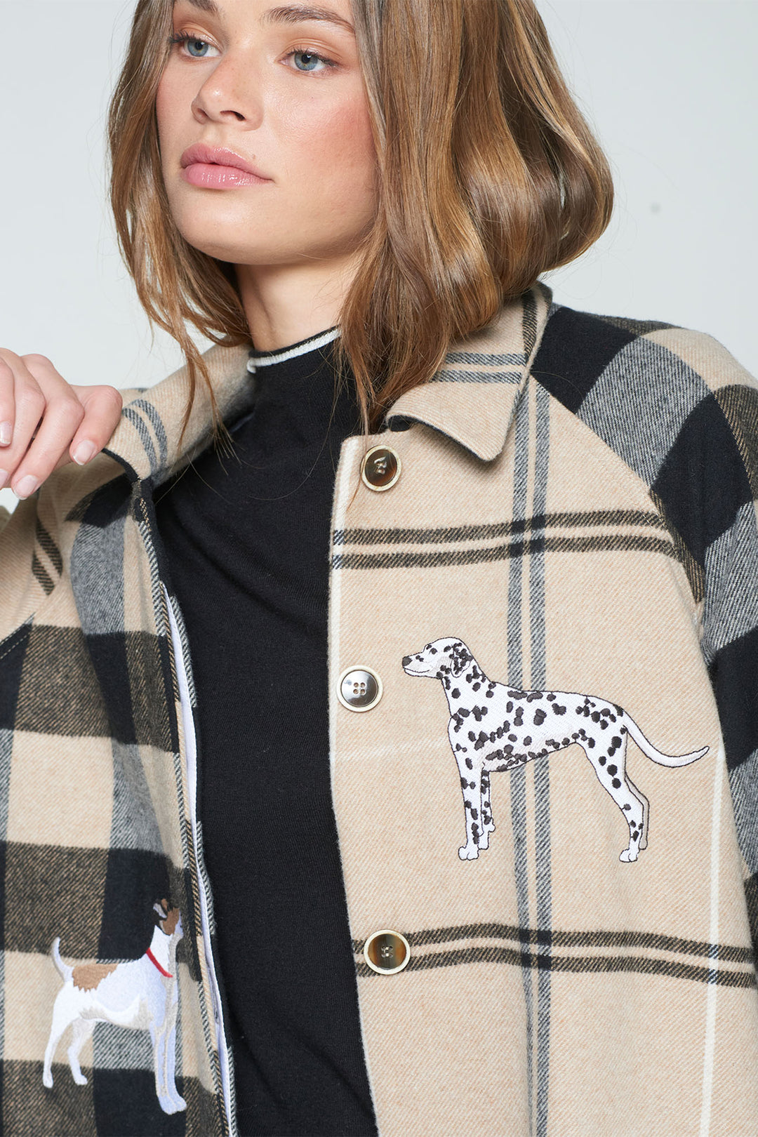 Person wearing a plaid coat with dog illustrations on a plain background