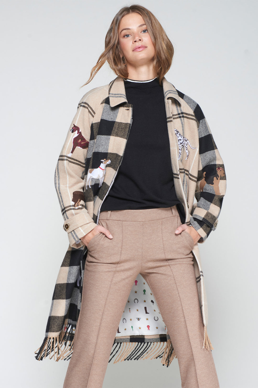 Woman wearing a plaid coat with embroidered designs on a plain background