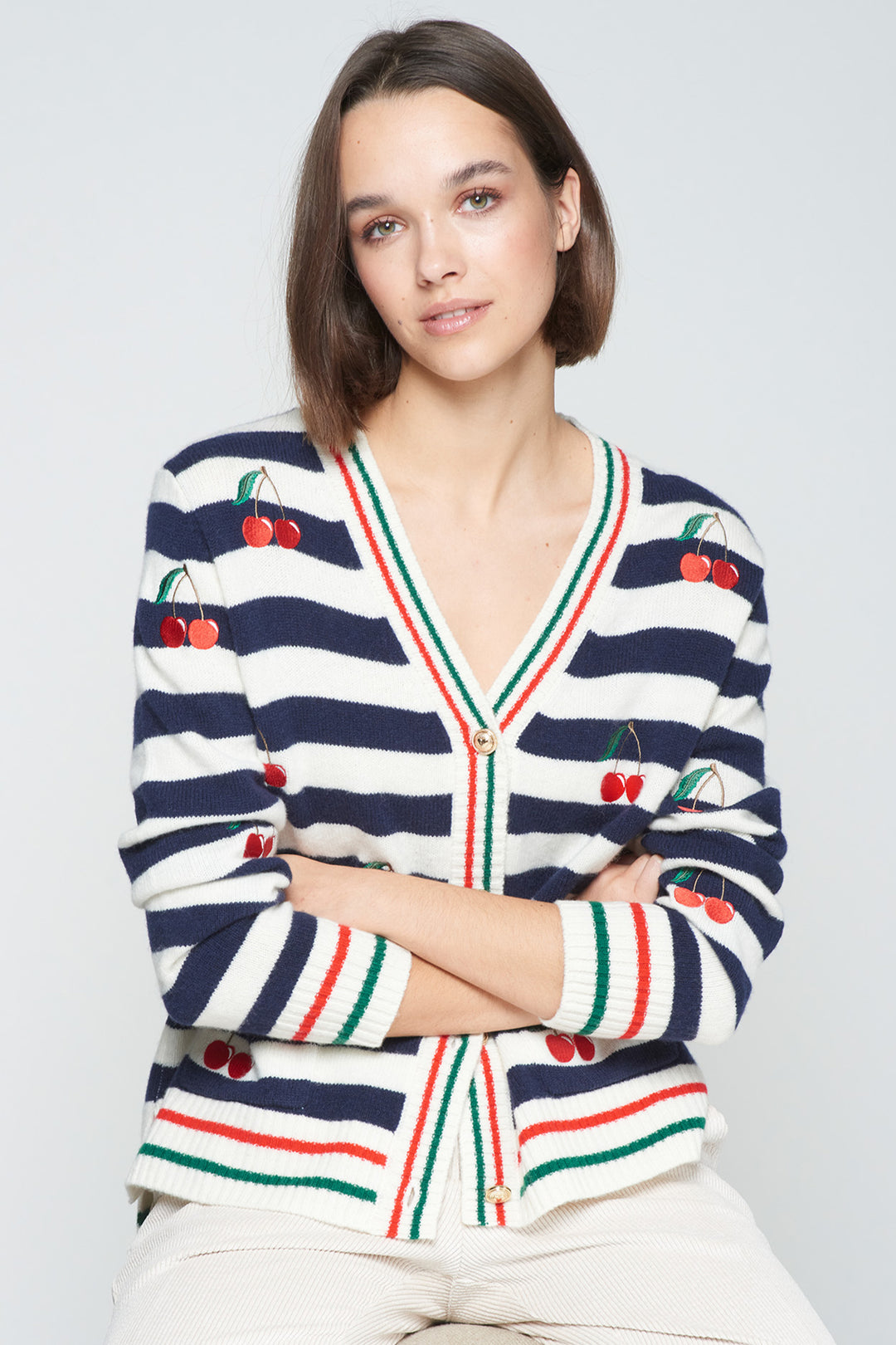 Woman wearing a striped sweater with cherry designs on a light gray background