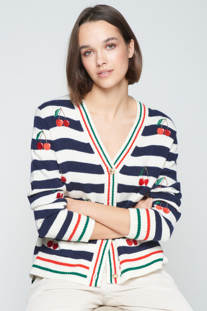 Woman wearing a striped sweater with cherry designs on a light gray background