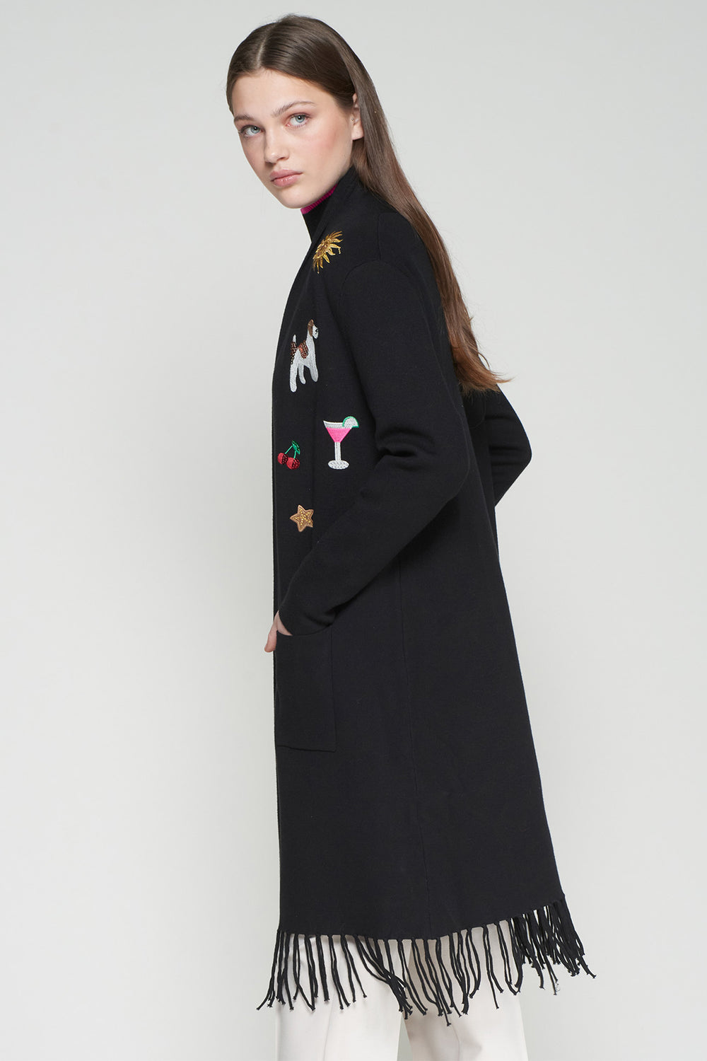 Black long coat with fringe details and embroidered designs on a white background