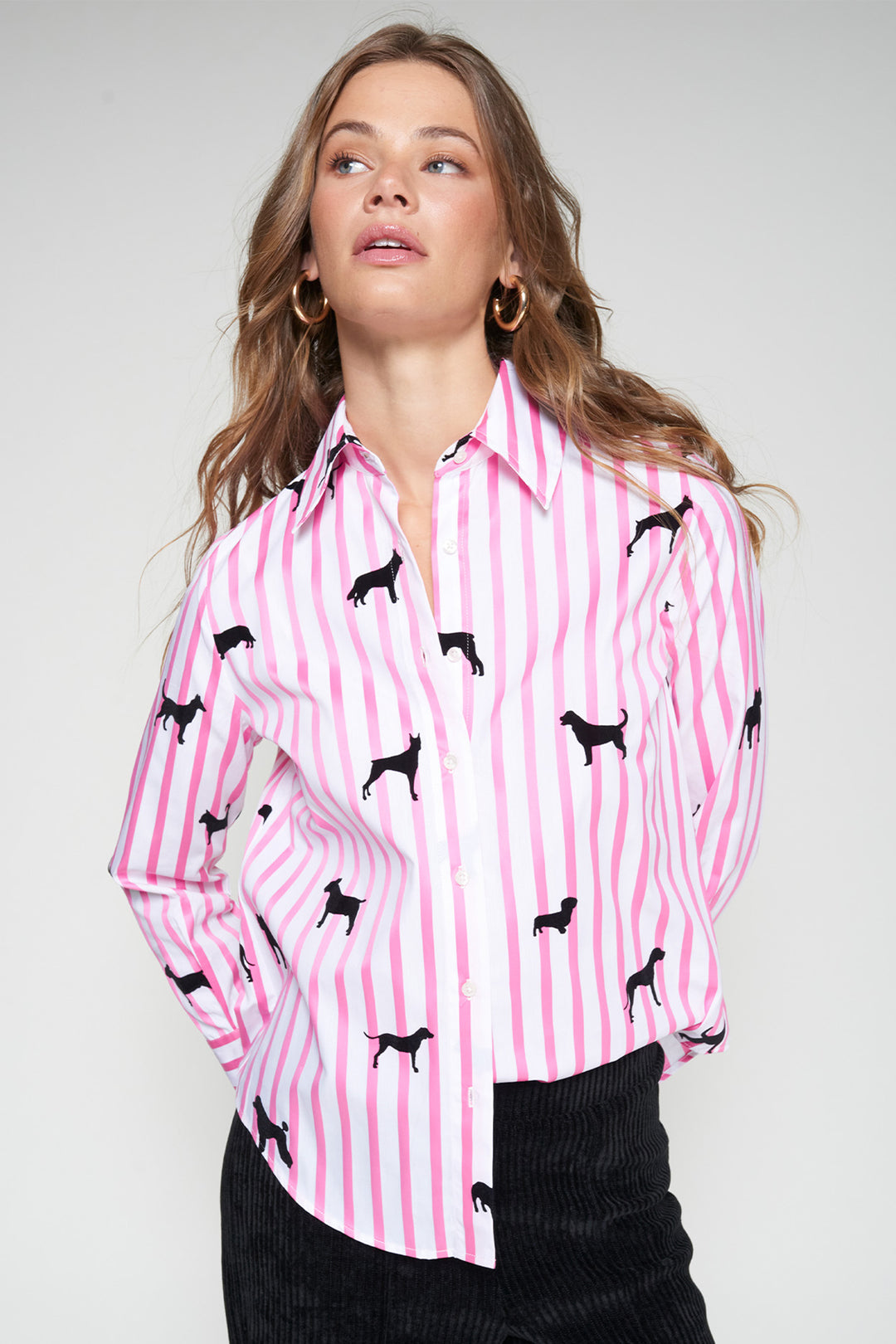 Woman wearing a pink and white striped shirt with black dog print on a plain background