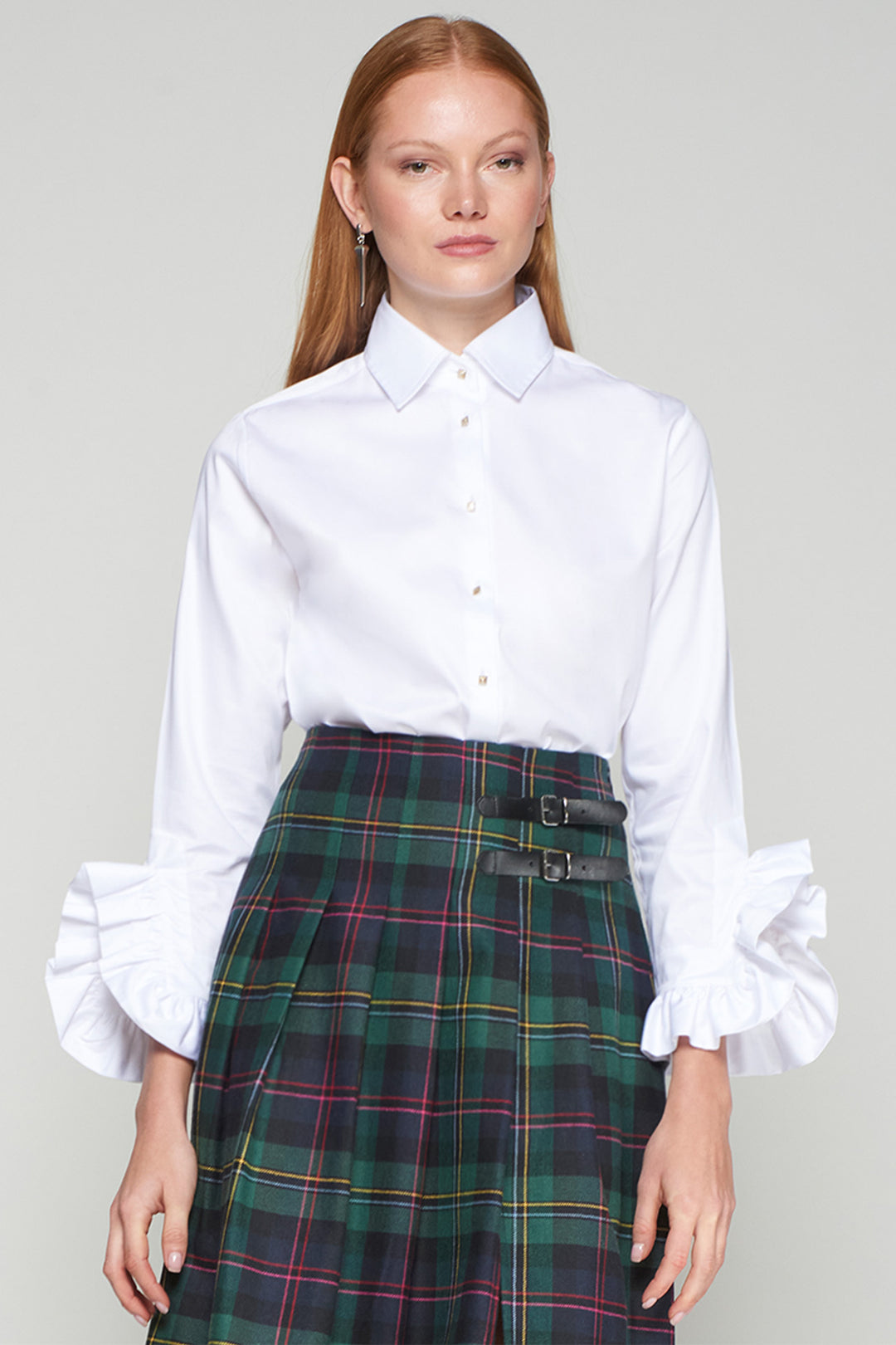 Woman wearing a white shirt and plaid skirt on a plain background