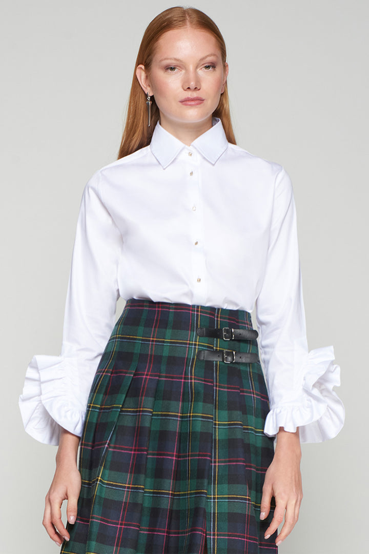 Woman wearing a white shirt and plaid skirt on a plain background