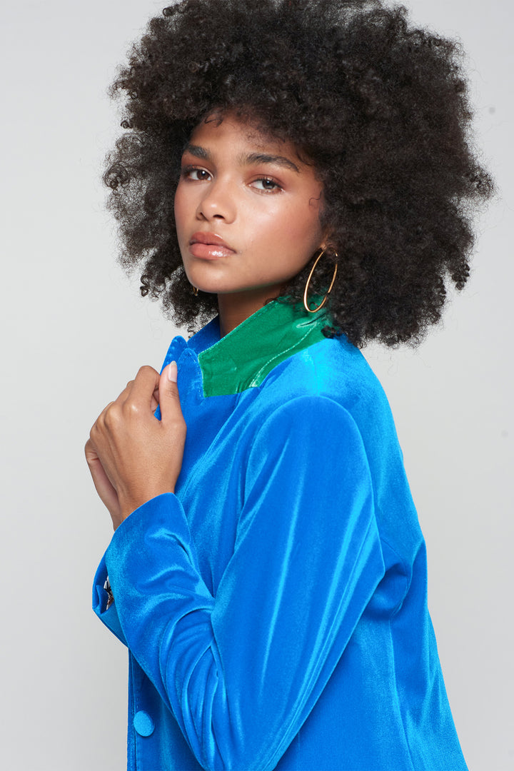 Woman wearing a blue jacket with a green collar against a plain background