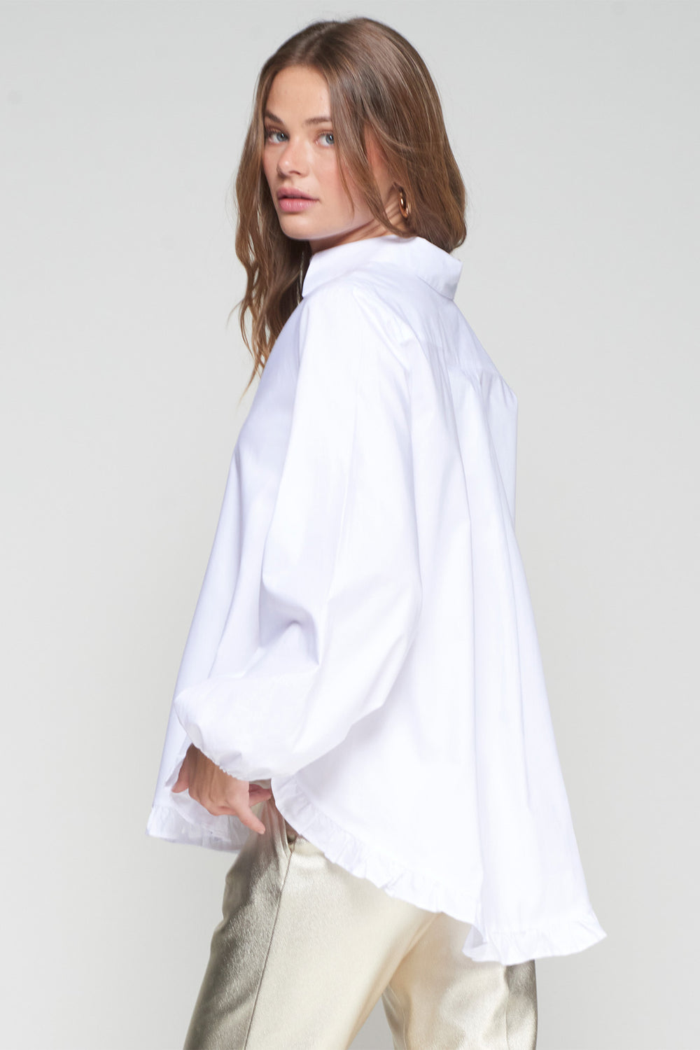 Woman wearing a white oversized shirt against a plain background