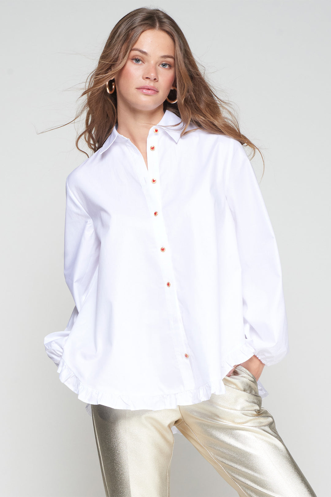 Woman wearing a white shirt with orange buttons against a plain background