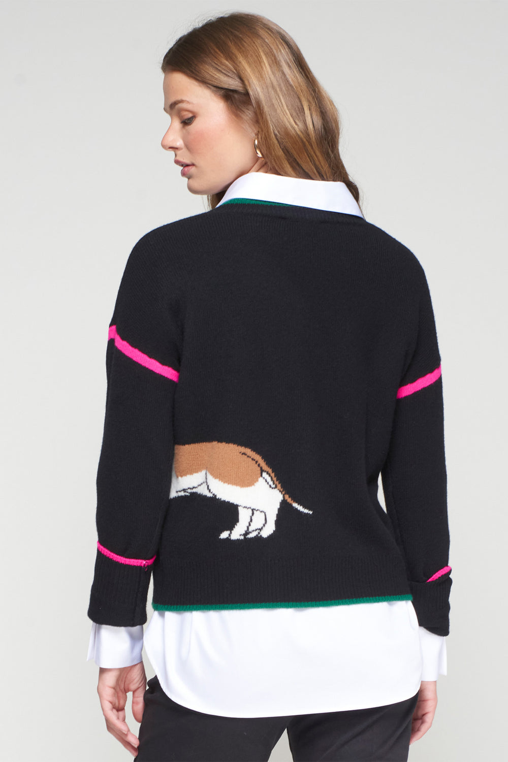 Woman wearing a black sweater with a horse design on a plain background