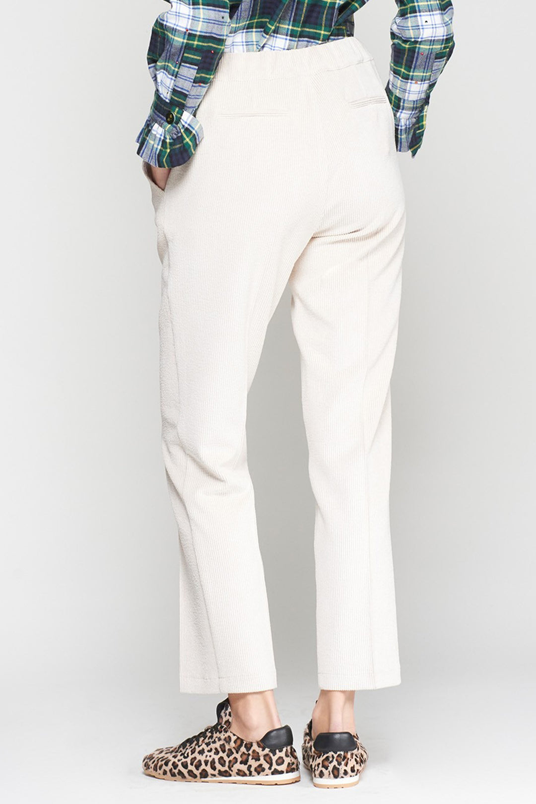 Person wearing white pants and a plaid shirt with leopard print shoes on a white background
