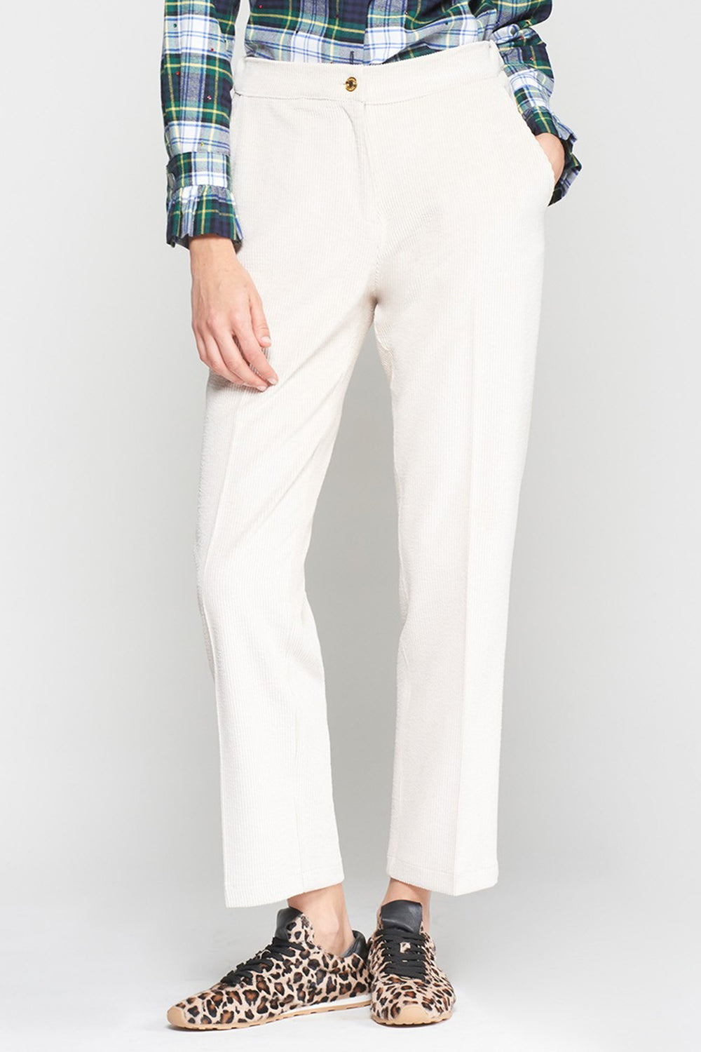 Person wearing white pants with a plaid shirt and leopard print shoes on a white background